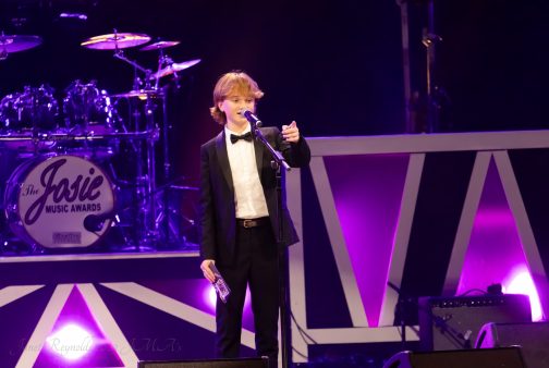 Singer Cormac Thompson - dressed in black tie - accepting a Josie award on stage in America